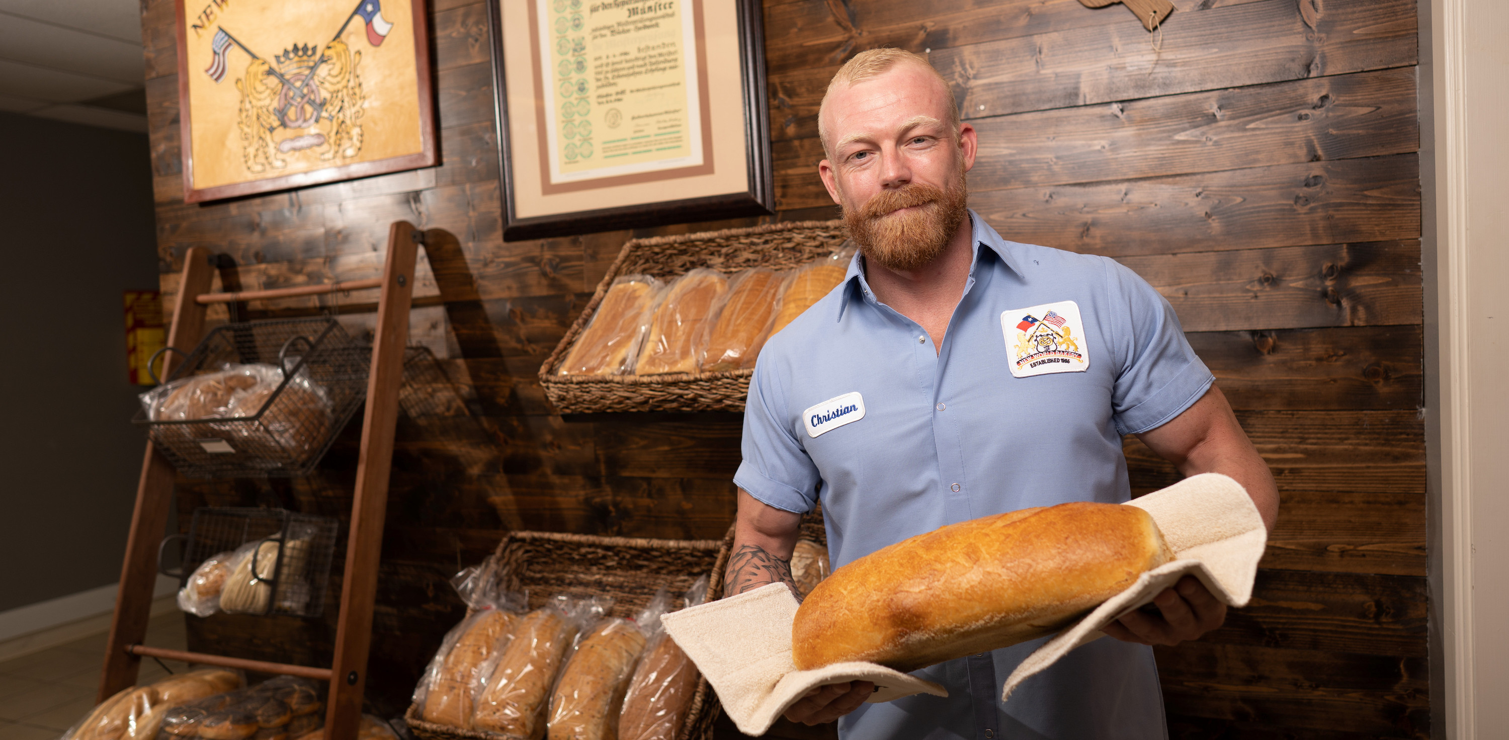 New world bakery employee showing off a freshly baked piece of bread