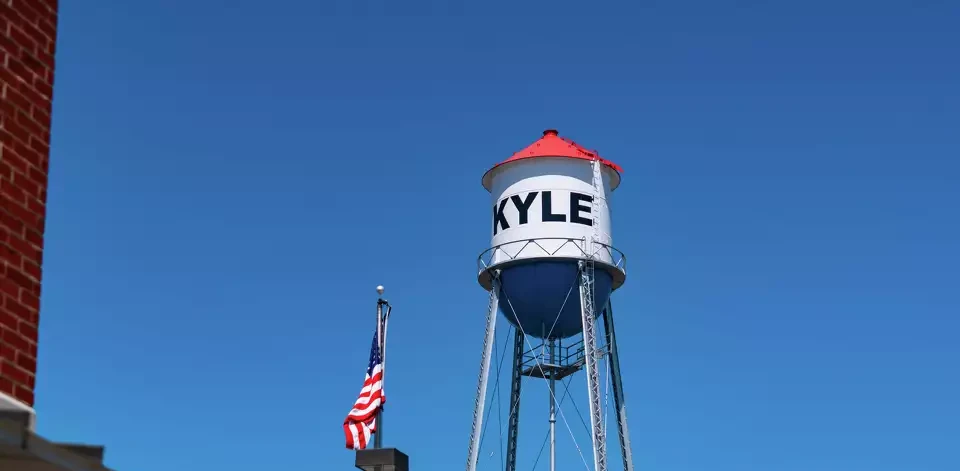 Red, white, and blue Water Tower in Small Town Texas with an American Flag with blue sky in Central Texas town Kyle , Texas , USA