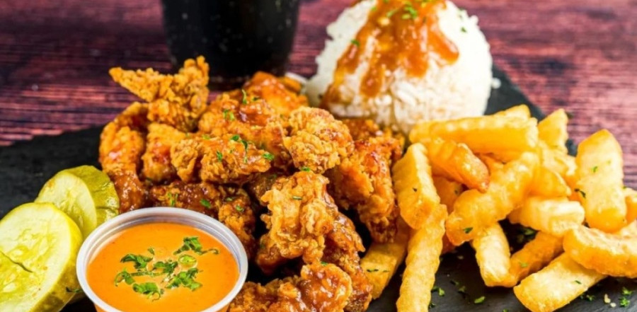 Photo of hot chicken plate with chicken, sauce, fries, rice and 2 pickle slices