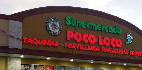 Storefront of Poco Loco at dusk with signs lit up and vehicles in front.