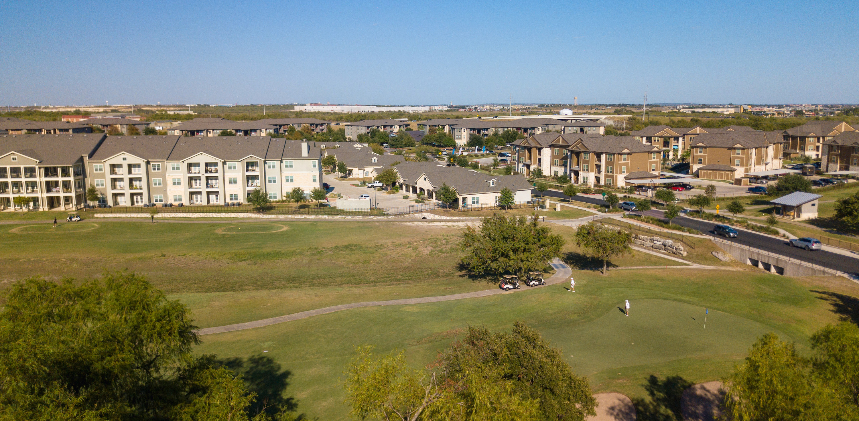 Drone shot of golf course with apartments in the background