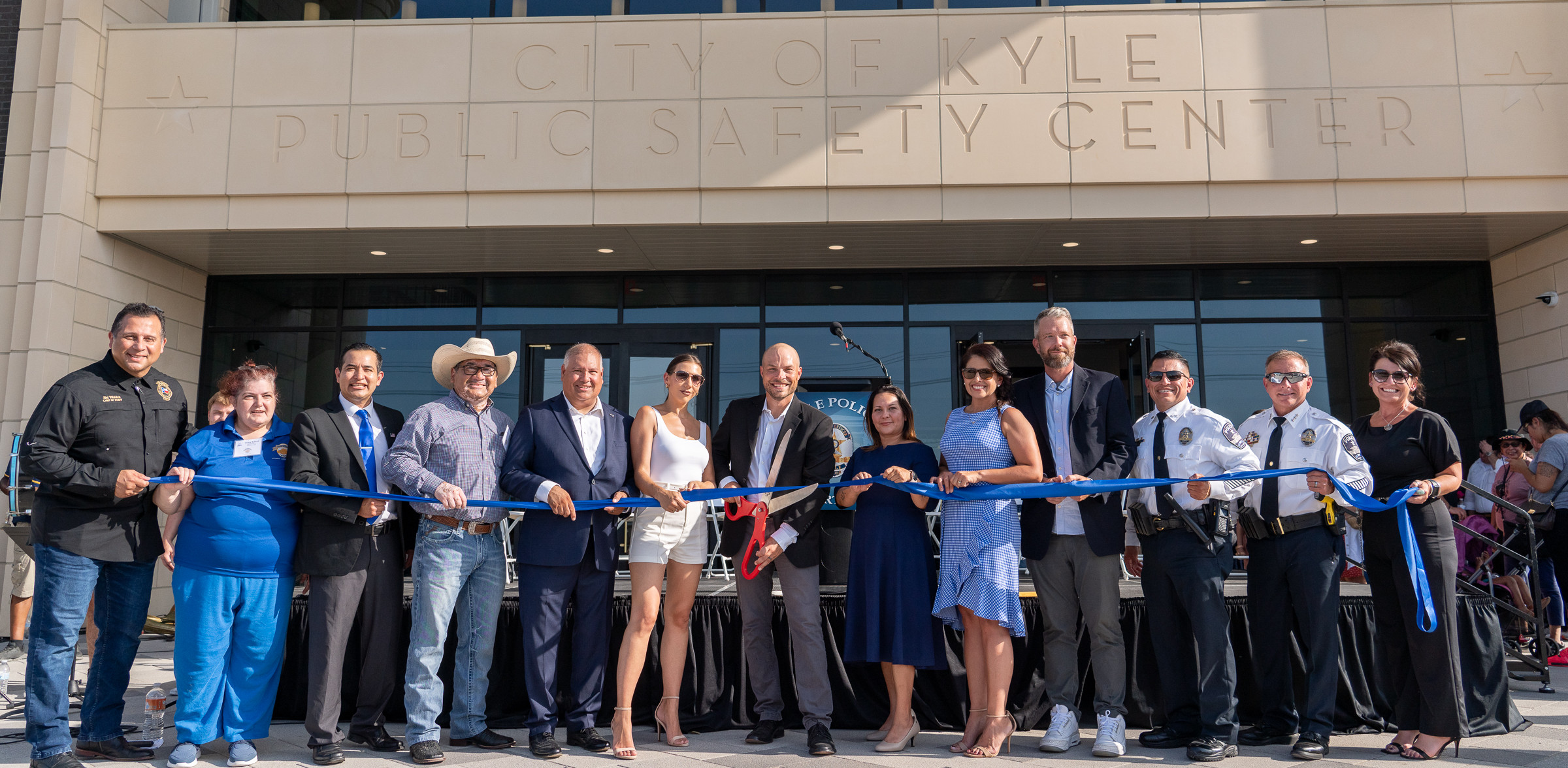 Mayor, council, former council, and staff cutting blue ribbon in front of new Public Safety Building