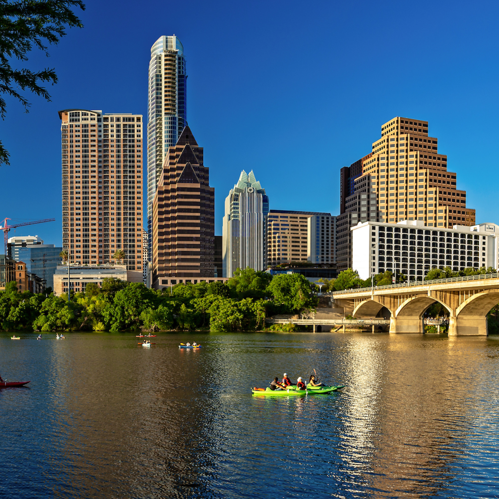 View of downtown buildings across from a lake with canoes in the water